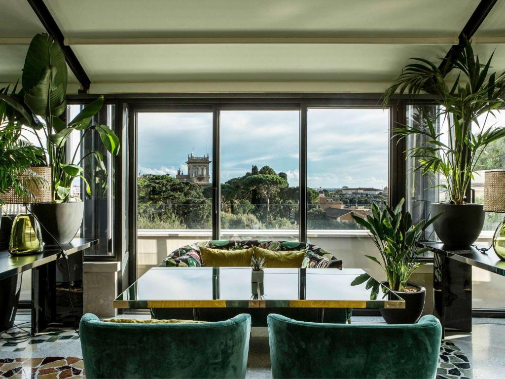 罗马Sofitel Roma Villa Borghese的客厅配有桌椅和大窗户