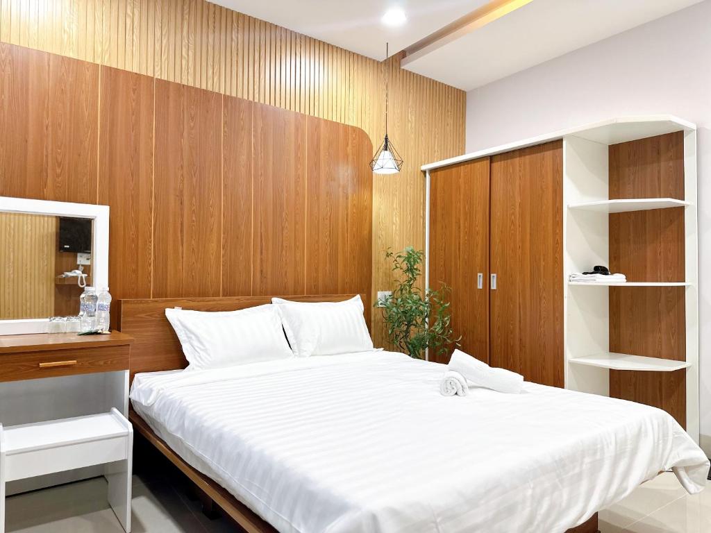 头顿Milanesa Hotel and Apartment的卧室设有白色大床和木墙