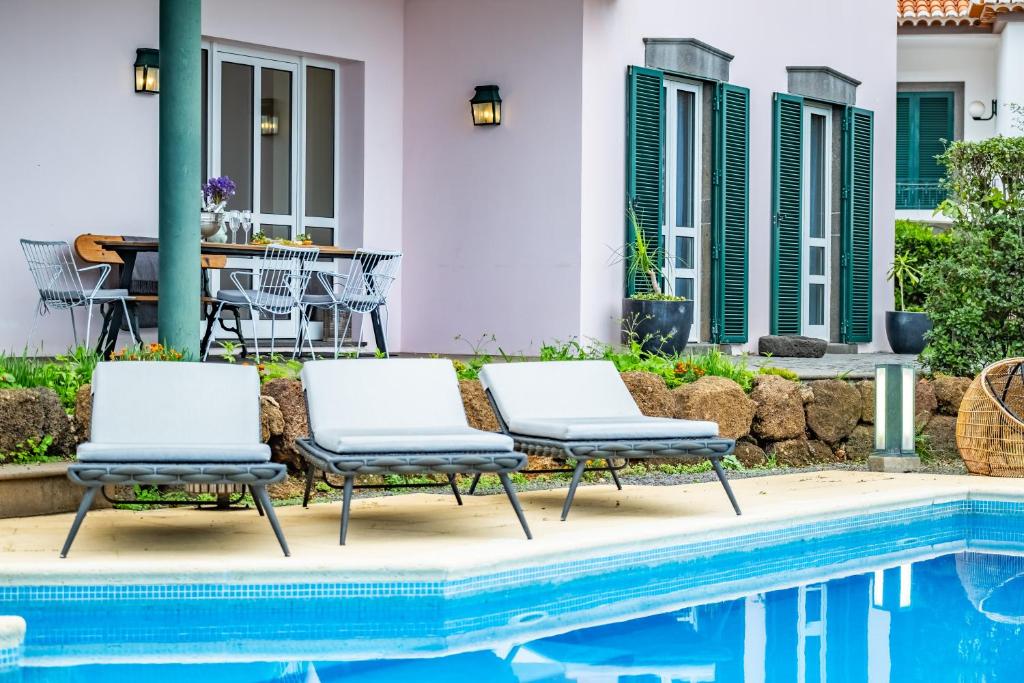 丰沙尔Villa Magnólia的游泳池畔的两把椅子和一张桌子