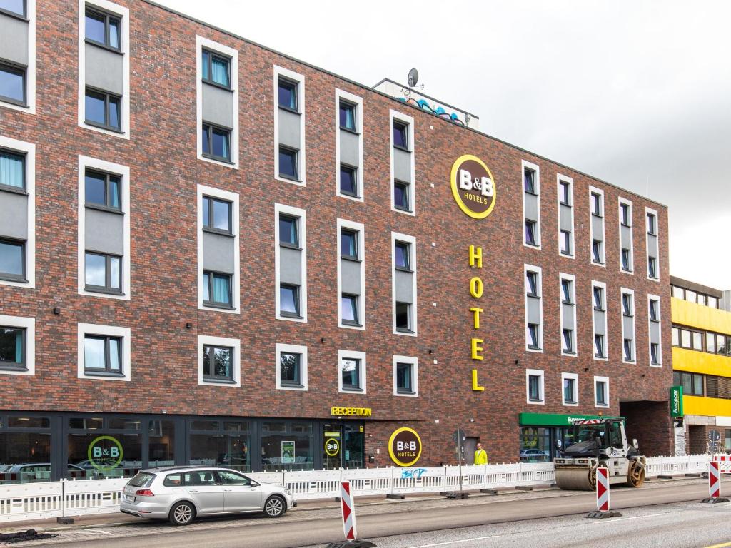 汉堡B&B Hotel Hamburg-Wandsbek的一座大型砖砌建筑,前面有一辆汽车