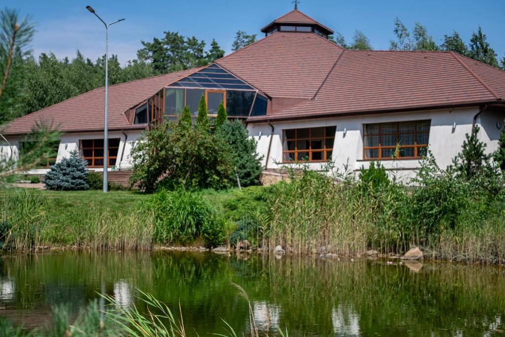 PodvorkiResto Park Традиція的前面有池塘的房子