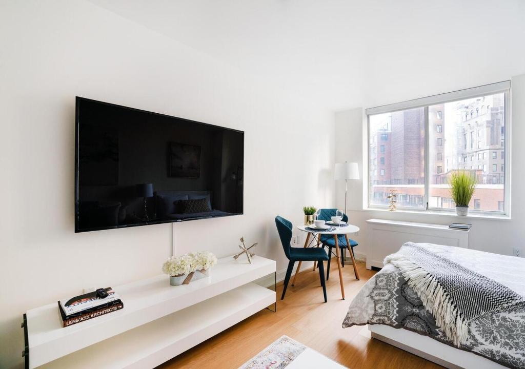 纽约Modern Studio Apartment At East Side的白色卧室配有壁挂式大屏幕平面电视