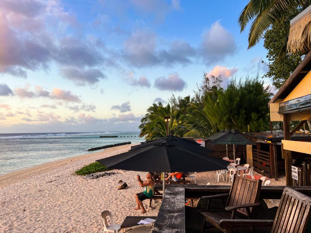 拉罗汤加流浪者度假酒店的坐在海滩上伞下的女人