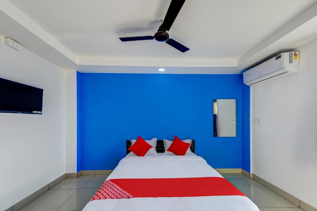 KhandagiriSPOT ON Hotel Utrishree的一间卧室设有蓝色的墙壁和一张带红色枕头的床。
