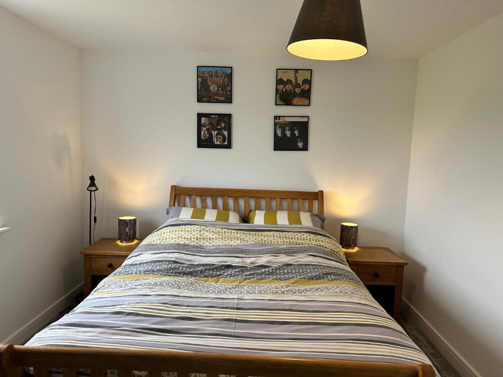 凯恩舍姆Bath and Bristol peaceful countryside home的卧室内的一张床位,配有两个床头柜和墙上的照片