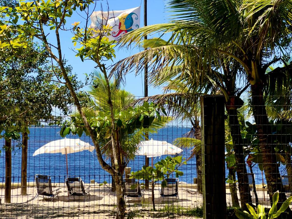巴拉那州蓬塔尔Pousada Vila do Mel的海滩上设有椅子和遮阳伞,还有大海