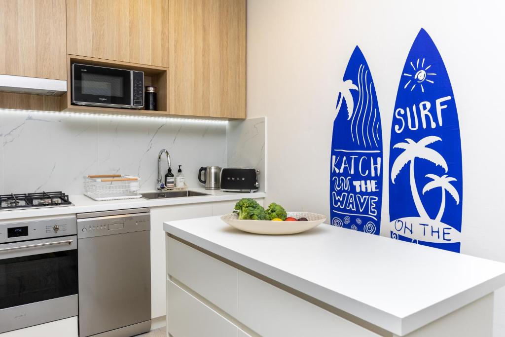 悉尼2BR Bondi Beauty - Elena by the Sea的厨房配有冲浪板标志和一碗水果