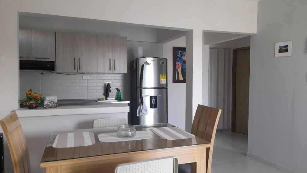 辛塞莱霍Acogedor apartamento Malala's的厨房配有桌子和不锈钢冰箱。