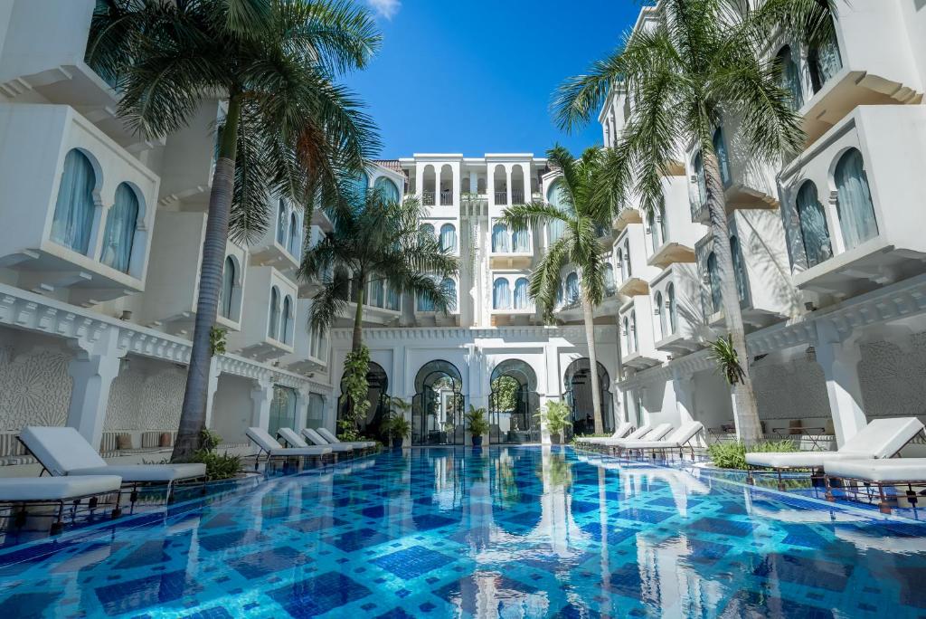 暹粒Sarai Resort & Spa and The Wander的棕榈树酒店庭院内的游泳池