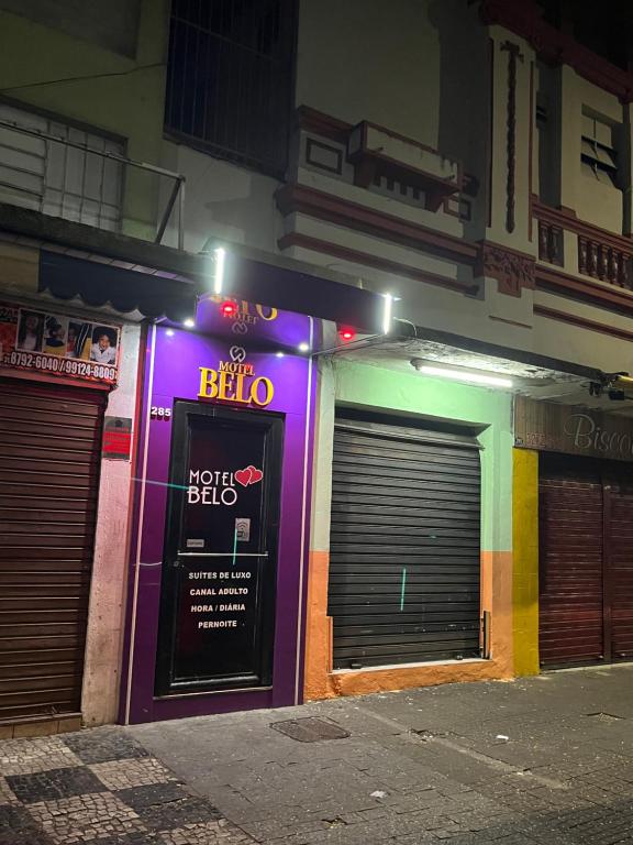 贝洛奥里藏特Belo Motel的一座带两个车库门和 ⁇ 虹灯标志的建筑