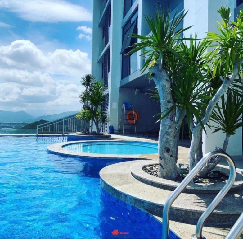 芽庄scenia bay residence Nha Trang的一座棕榈树游泳池,位于酒店大楼旁