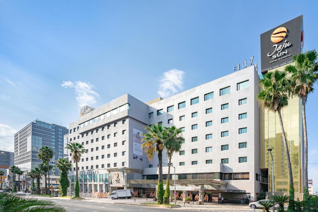 济州市济州岛阳光赌场酒店的一座白色的大建筑,前面有棕榈树