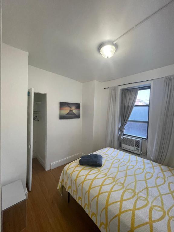 西纽约Room in a 2 Bedrooms apt. 10 minutes to Time Square!的一间卧室配有一张带黄色毯子和窗户的床