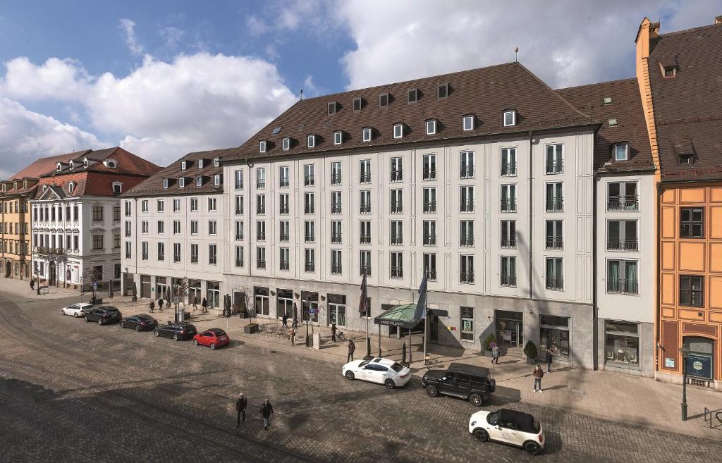 奥格斯堡Hotel Maximilian’s的一条白色的大建筑,汽车停在街上