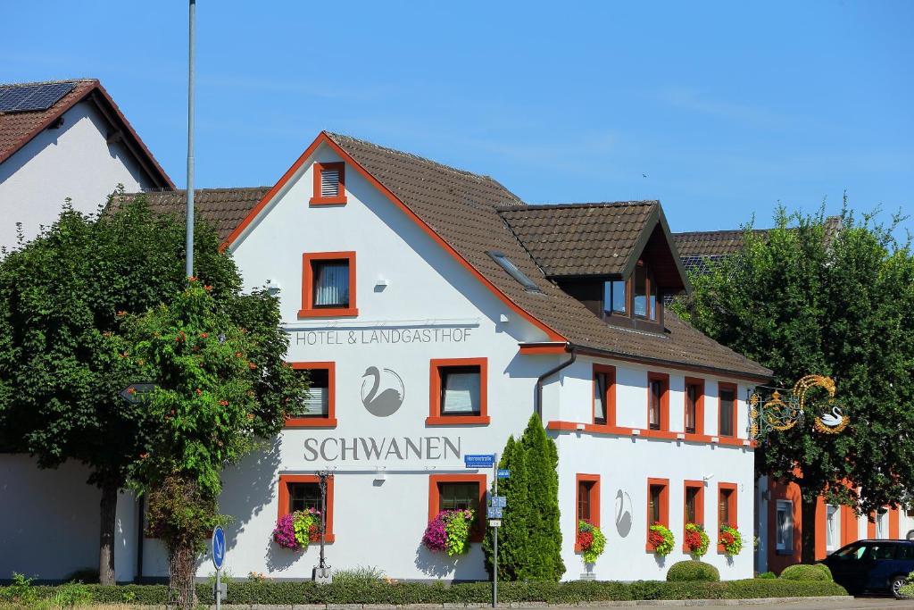 莱茵河畔凯尔Hotel Schwanen的白色的建筑,上面有标志