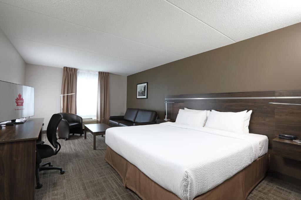 布兰登Canad Inns Destination Centre Brandon的酒店客房设有一张大床和一张书桌。