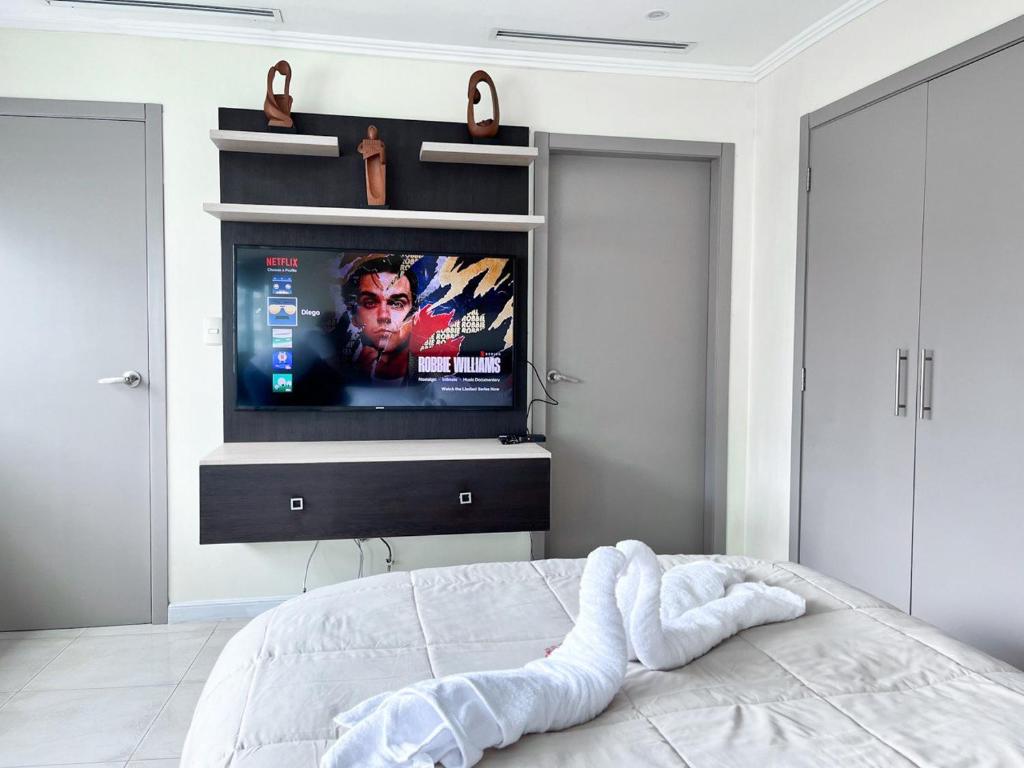 瓜亚基尔Depa de lujo con piscina y jacuzzi的一间卧室设有一张带平面电视的床。