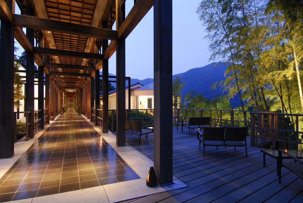 箱根强罗花坛传统日式旅馆的一个带桌椅和顶棚的甲板,背景是群山