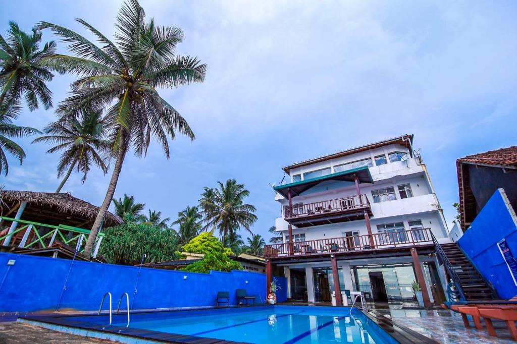 希克杜沃Hotel Wewala Beach的一座带游泳池和棕榈树的建筑
