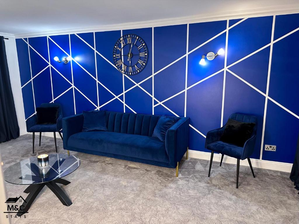 凯特林Kettering/Stylish/ Perfect for Contractors的客厅配有蓝色的沙发和墙上的时钟