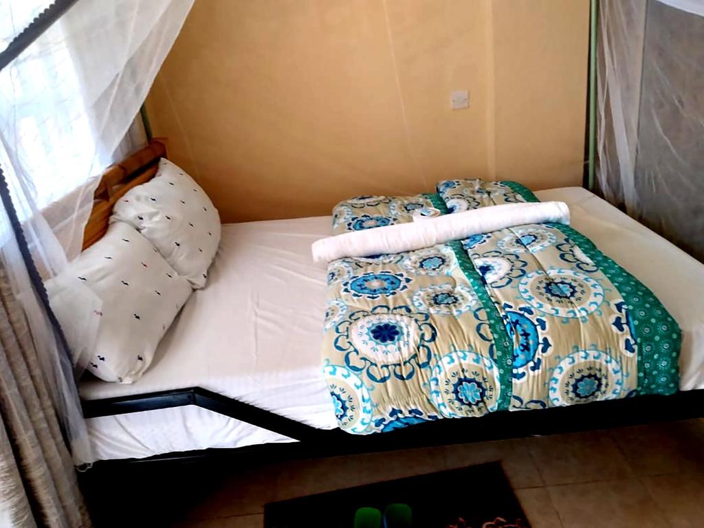 BungomaVILLA DE LEO的一张带两个枕头的小床和毯子
