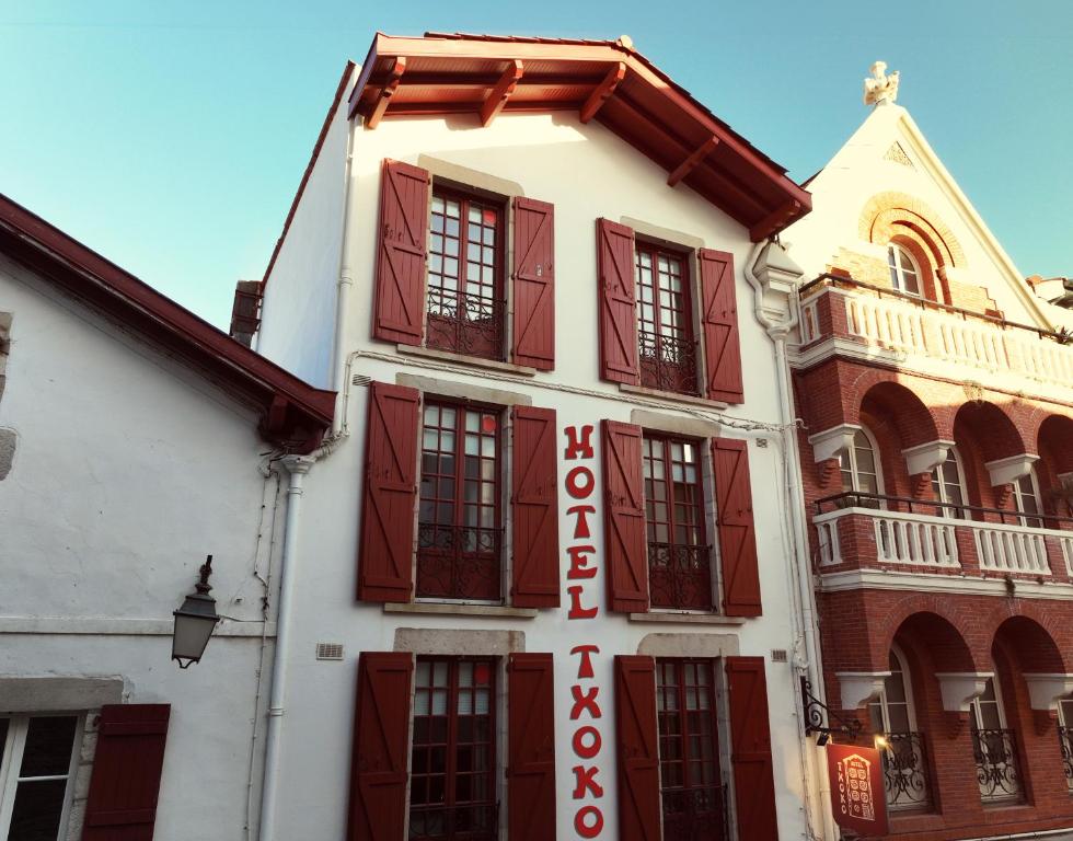 圣让-德吕兹Boutique Hôtel Txoko的白色的建筑,上面有红色的百叶窗