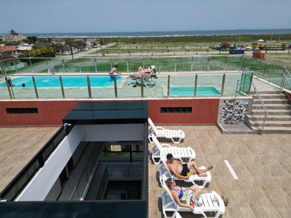巴拉那州蓬塔尔Hotel Amaromar的几个人坐在游泳池旁的椅子上