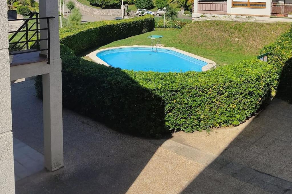 莫格罗Apartamento en Mogro.的一座被灌木丛环绕的游泳池,位于一座建筑旁边