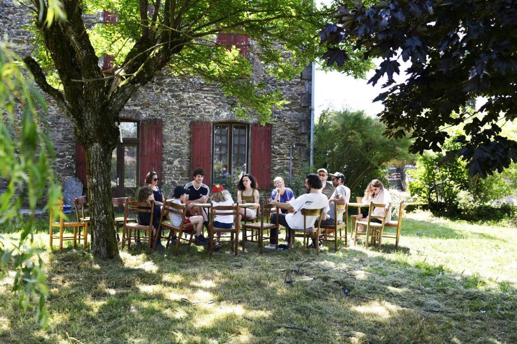 Salles-CuranLa Villa Bouloc, gite pour la famille的一群人坐在大楼前的桌子上
