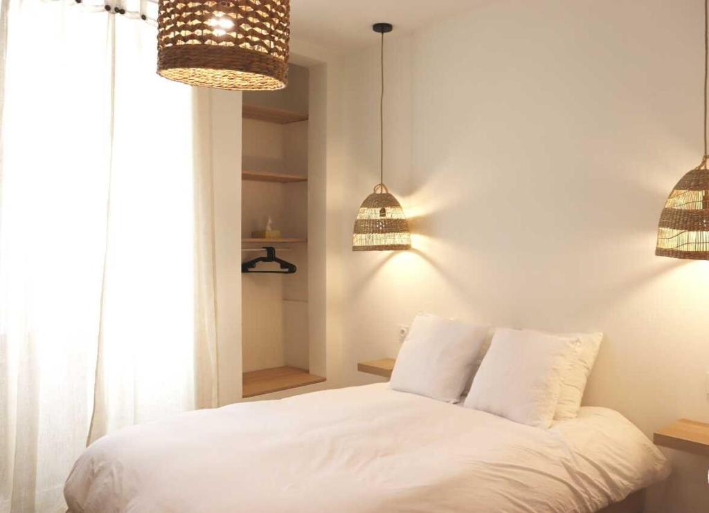 坦耶尔米塔格Charmant studio en plein coeur de Tain l'Hermitage的卧室配有白色的床和2盏吊灯。