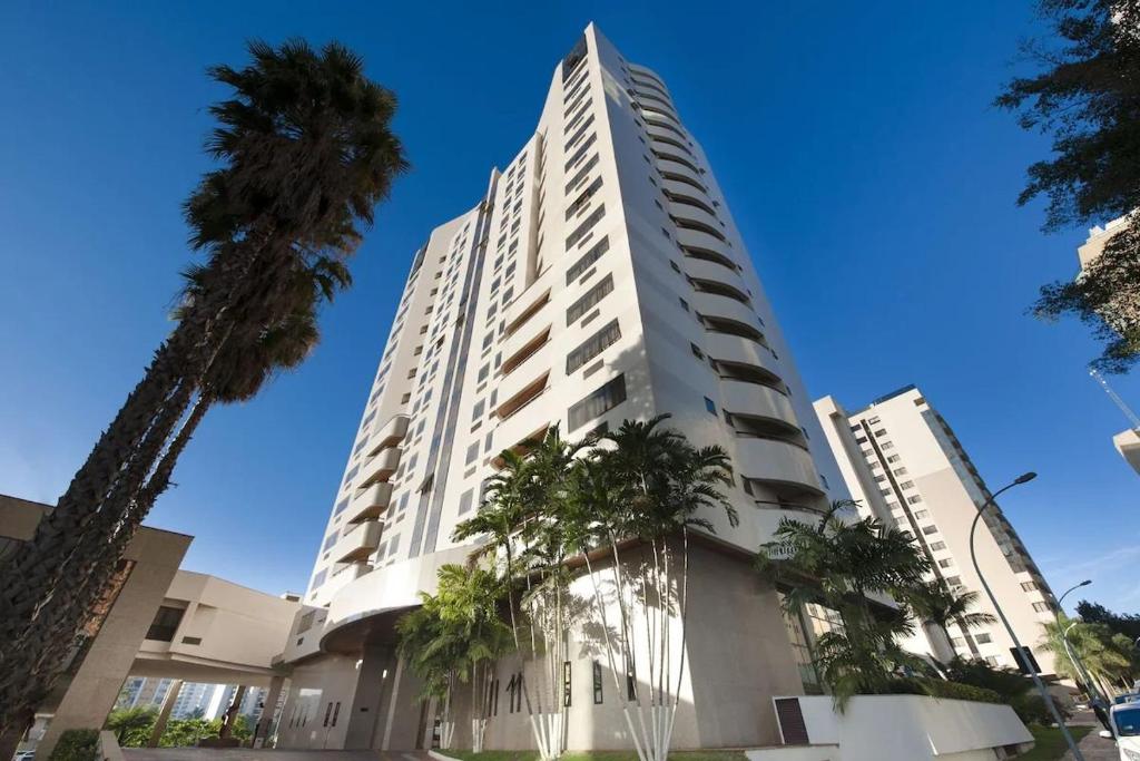 巴西利亚Flat Particular no Comfort Suites的一座高大的白色建筑,前面有棕榈树