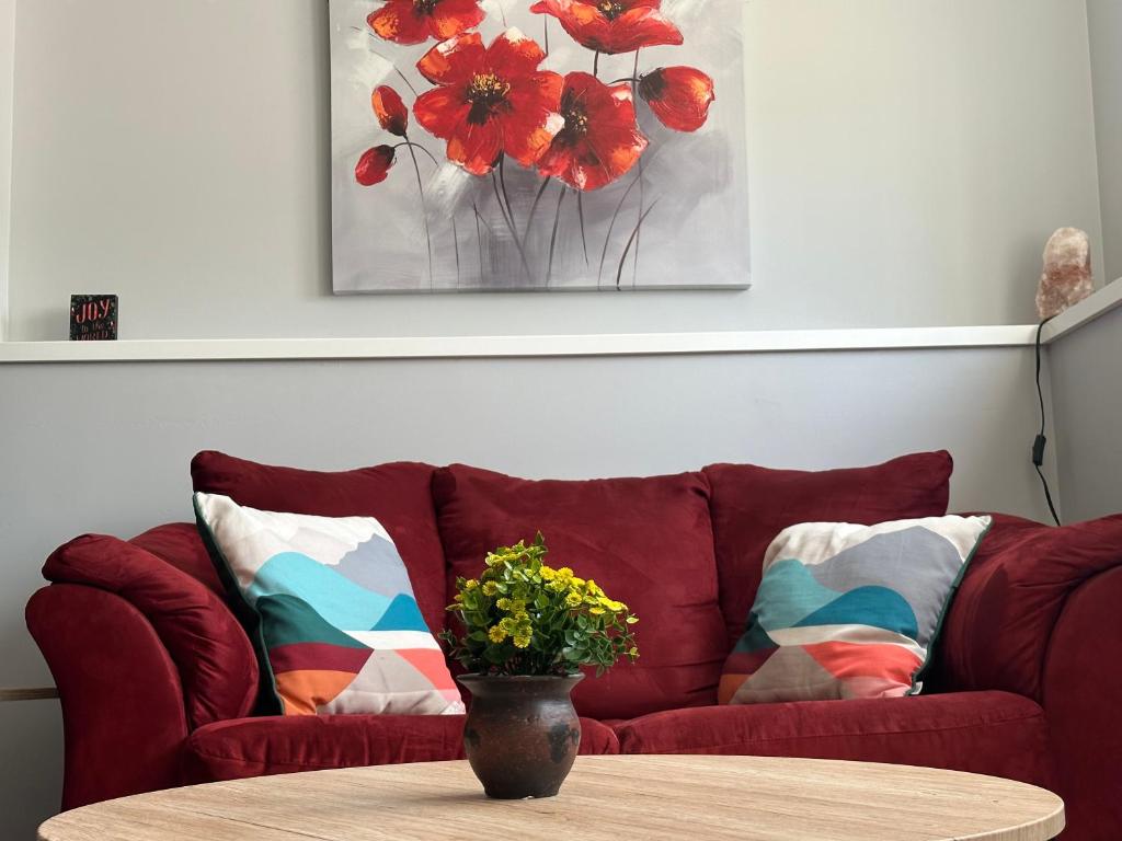 萨斯卡通Exquisite Cozy Suite/full amenities in Kensington的红色的沙发,上面有桌子和花瓶