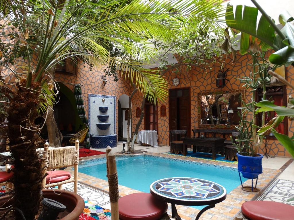 马拉喀什Riad Sérénis的一座带植物和桌子的庭院内的游泳池