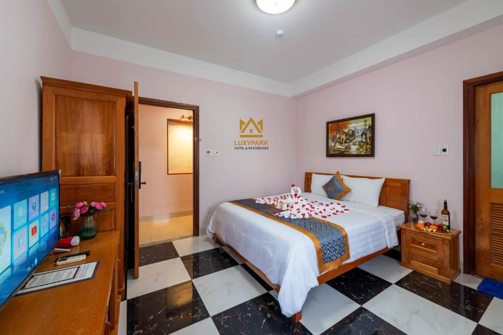 富国Luxy Park Hotel & Residences - Phu Quoc City Centre的一间卧室配有一张床和一台平面电视
