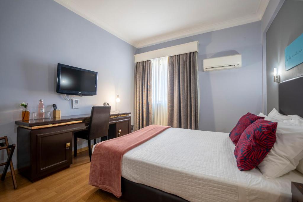 维塞乌奥尼克斯酒店的配有一张床和一张书桌的酒店客房