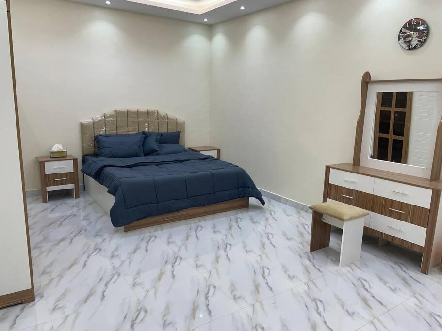 Qufārشاليه راقي بمسطحات خضراء وغرفة نوم的一间卧室配有一张带蓝色床单和镜子的床