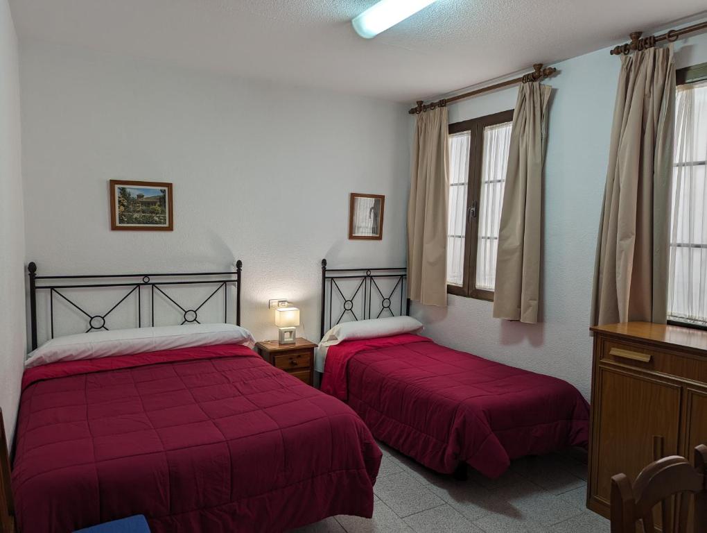 格拉纳达纳瓦罗拉莫斯城市旅馆的宿舍间的两张床,配有红色床单和窗户
