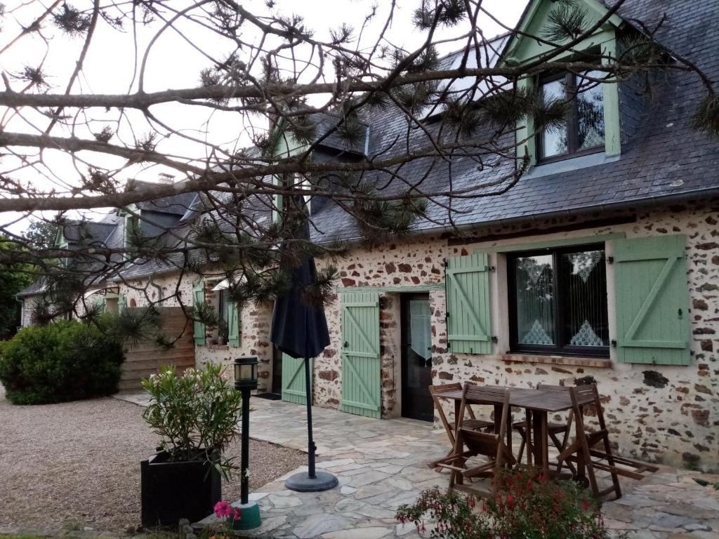 Saint-Ouen-des-ToitsChambre d hote La Roussiere的一座带绿门的房子,房子前面有一张桌子