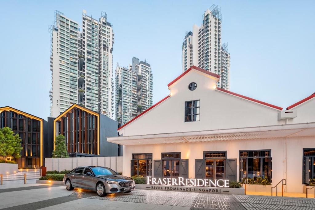 新加坡Fraser Residence River Promenade, Singapore的停在高楼前的汽车