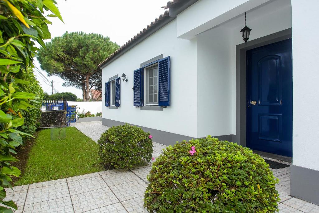 蓬塔德尔加达Capelas Blue , Relax & Fun - Up to 14 Guests!的白色的房子,有蓝色的门和灌木