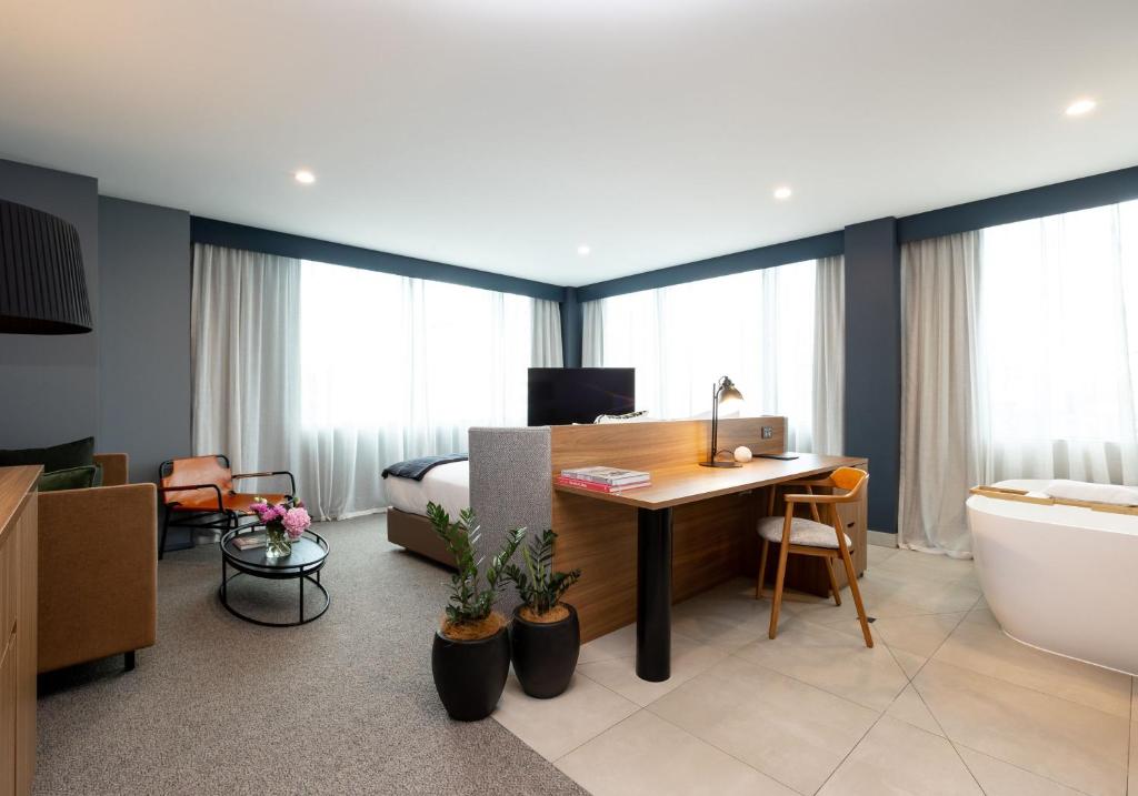 奥克兰Sudima Auckland City的酒店客房设有书桌和卧室。