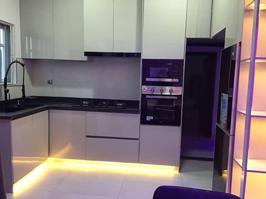 RumodomeBrandison Apartments的厨房配有白色橱柜和带灯具的电器