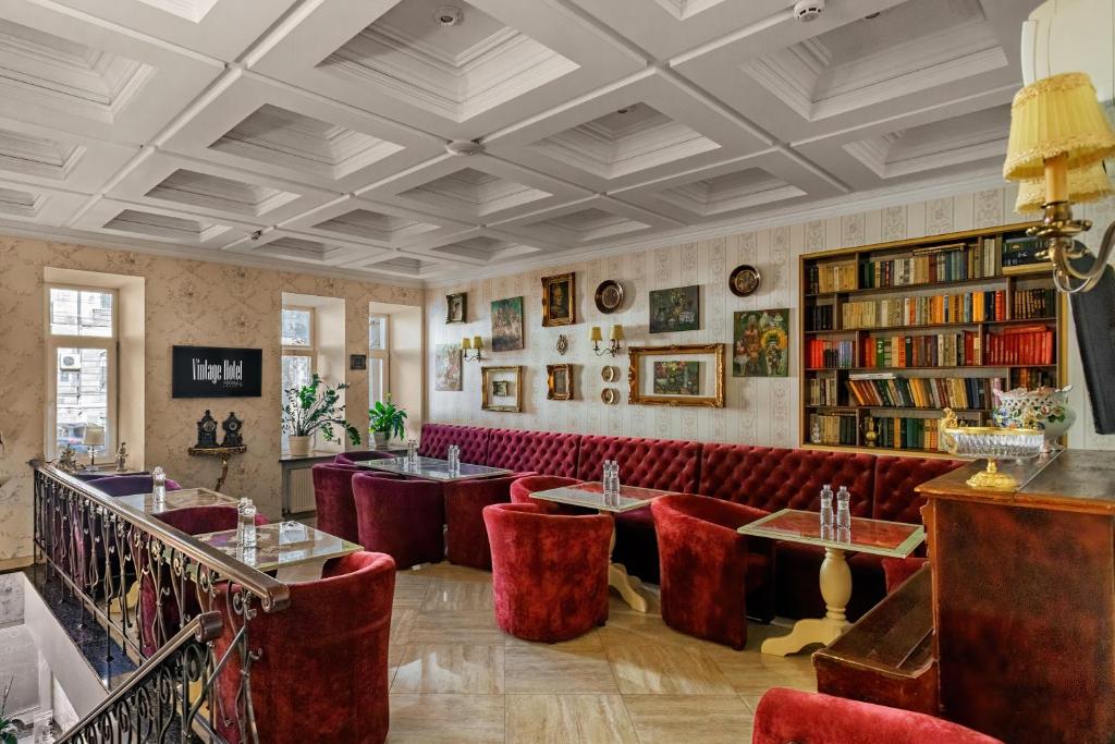 敖德萨Vintage Art Hotel的一间设有红色椅子和桌子及书籍的餐厅