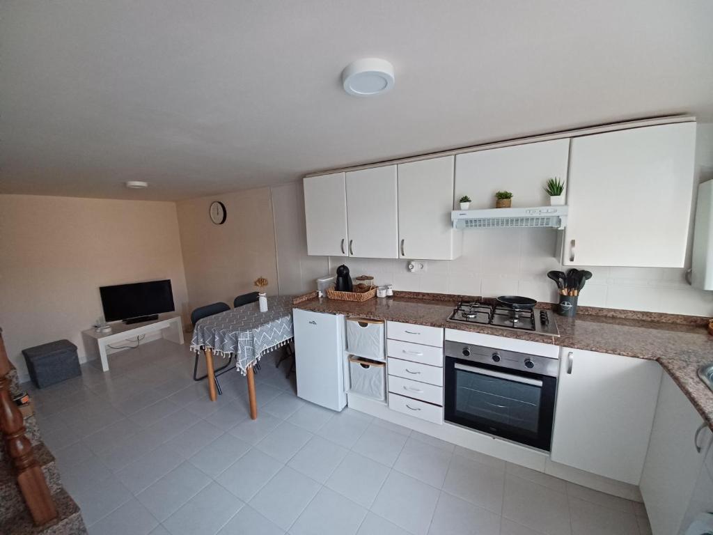 PaderneCasa Montecelo的厨房配有白色橱柜、桌子和电视。