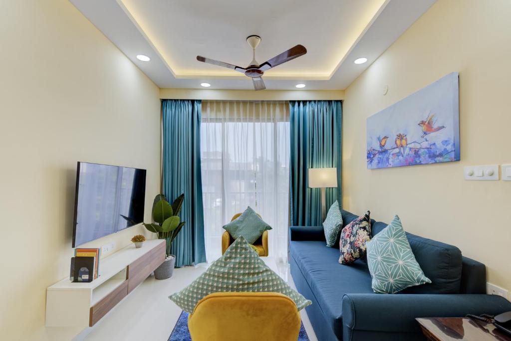 达波林Luxe 2BHK by Coral BnB with Pool access的客厅配有蓝色的沙发和电视