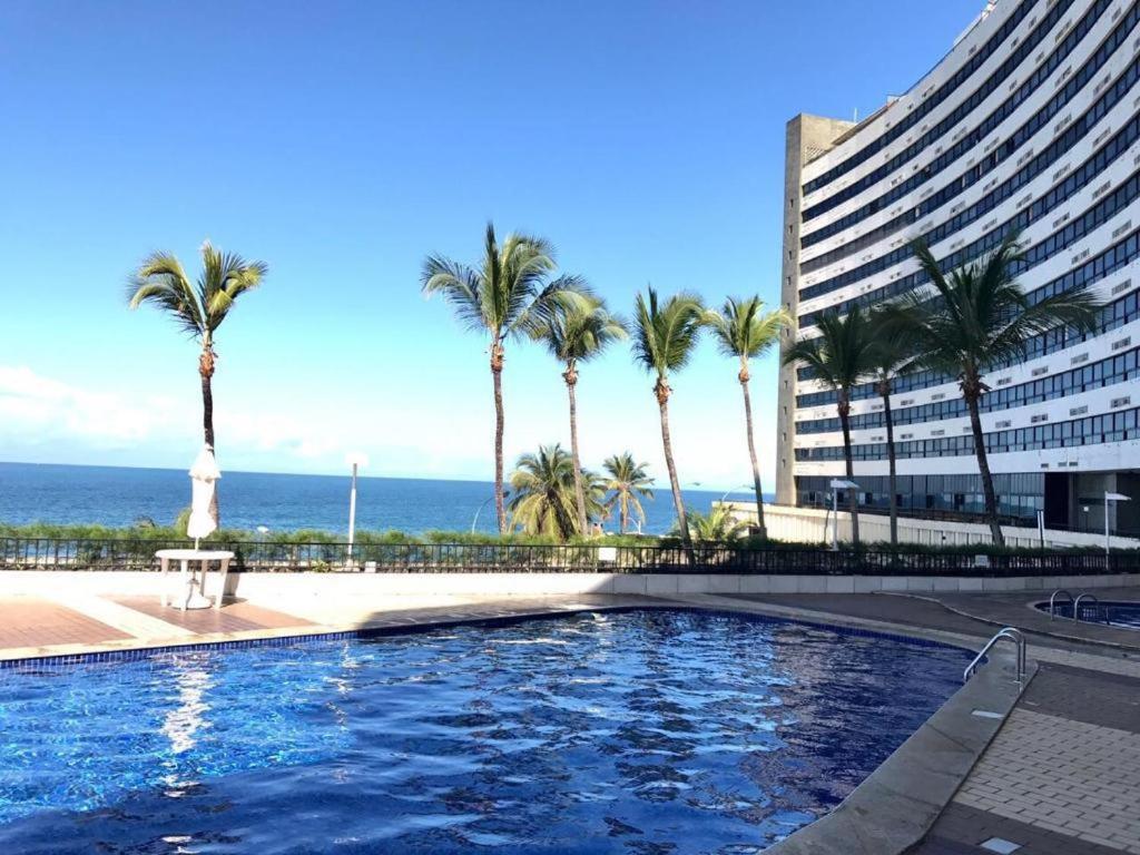萨尔瓦多apart hotel 2 quartos frente mar的一座楼前棕榈树游泳池