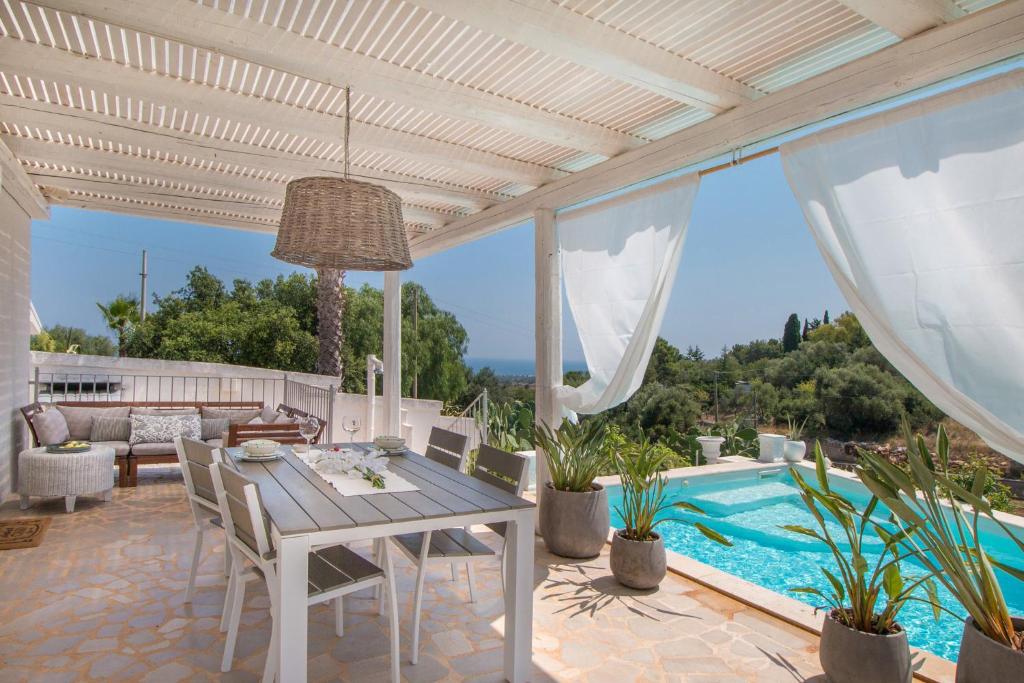 滨海波利尼亚诺Trulli Dimore - Casa Fusella的一个带桌椅的庭院和一个游泳池