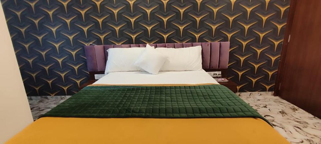 艾哈迈达巴德Hotel Shaswat Inn的一间卧室配有一张带绿色和黄色毯子的床