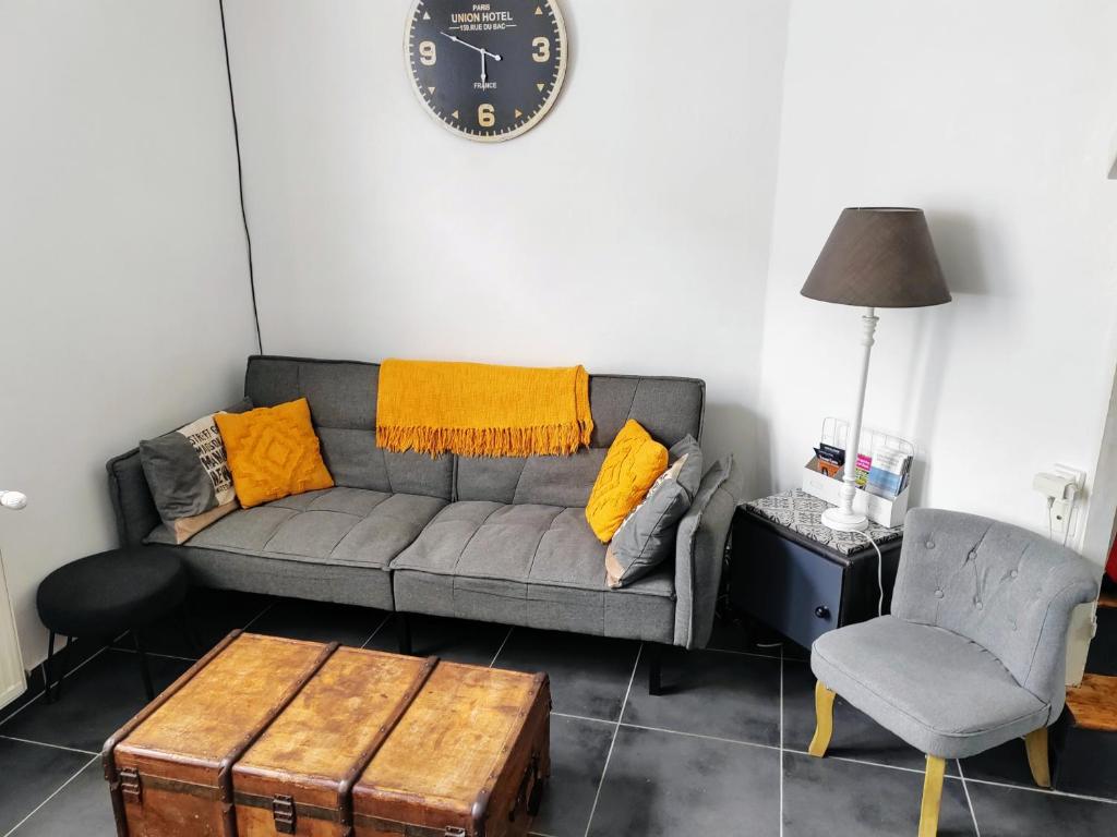 博韦LA PETITE MAISON的客厅配有沙发和墙上的时钟