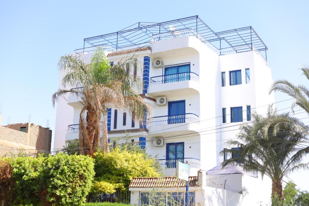 卢克索卡斯兰别墅公寓的白色的建筑,拥有蓝色的窗户和棕榈树